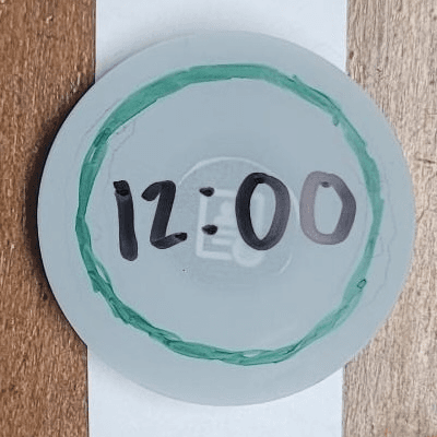 A paper prototype watch face showing the time and green ring.