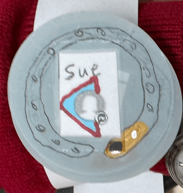 A paper prototype watch face showing the a phone contact named Sue and bold text saying URGENT.